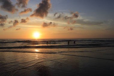 Endonezya 'da deniz ve plajın üzerinde güneş ve akşam gökyüzü batıyor