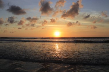 Endonezya 'da deniz ve plajın üzerinde güneş ve akşam gökyüzü batıyor