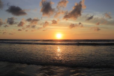 Endonezya 'da deniz ve plajın üzerinde güneş ve akşam gökyüzü batıyor