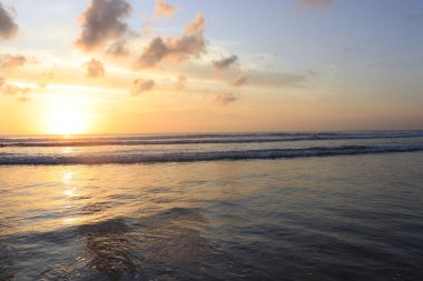 Endonezya 'da deniz ve plajın üzerinde güneş ve akşam gökyüzü batıyor