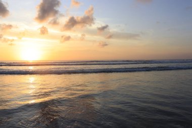 Endonezya 'da deniz ve plajın üzerinde güneş ve akşam gökyüzü batıyor
