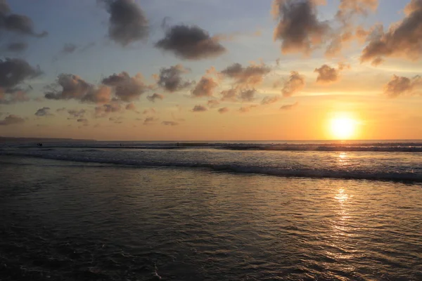 Endonezya 'da deniz ve plajın üzerinde güneş ve akşam gökyüzü batıyor