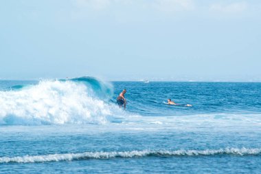 Endonezya 'daki Uluwatu Sahili yakınlarında okyanusta sörf yapan bir adamın uzaktan görünüşü