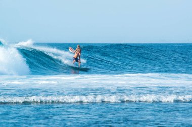 Endonezya 'daki Uluwatu Sahili yakınlarında okyanusta sörf yapan bir adamın uzaktan görünüşü