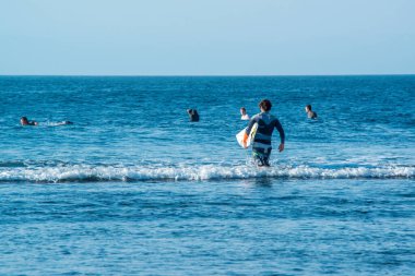Endonezya 'daki Uluwatu Sahili yakınlarında okyanusta sörf yapan bir adamın uzaktan görünüşü