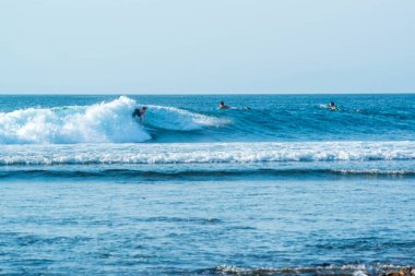 Endonezya 'daki Uluwatu Sahili yakınlarında okyanusta sörf yapan bir adamın uzaktan görünüşü