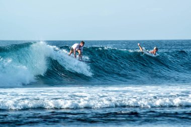Endonezya 'daki Uluwatu Sahili yakınlarında okyanusta sörf yapan bir adamın uzaktan görünüşü
