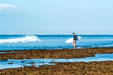Endonezya 'daki Uluwatu Sahili yakınlarında okyanusta sörf yapan bir adamın uzaktan görünüşü