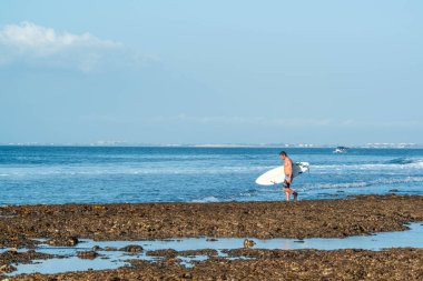 Endonezya 'daki Uluwatu Sahili yakınlarında okyanusta sörf yapan bir adamın uzaktan görünüşü