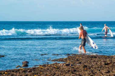 Endonezya 'daki Uluwatu Sahili yakınlarında okyanusta sörf yapan bir adamın uzaktan görünüşü