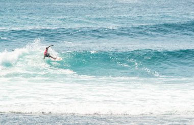 Endonezya 'daki Uluwatu Sahili yakınlarında okyanusta sörf yapan bir adamın uzaktan görünüşü