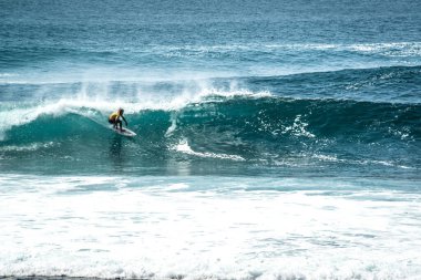 Endonezya 'nın Uluwatu Sahili yakınlarında okyanusta sörf yapan bir adam.
