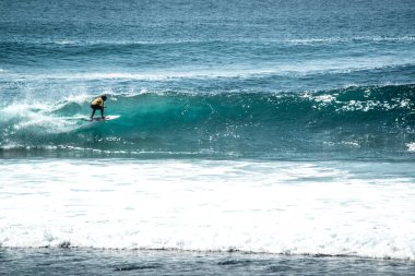 Endonezya 'nın Uluwatu Sahili yakınlarında okyanusta sörf yapan bir adam.
