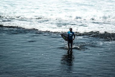 Endonezya 'nın Uluwatu Sahili yakınlarında okyanusta sörf yapan bir adam.