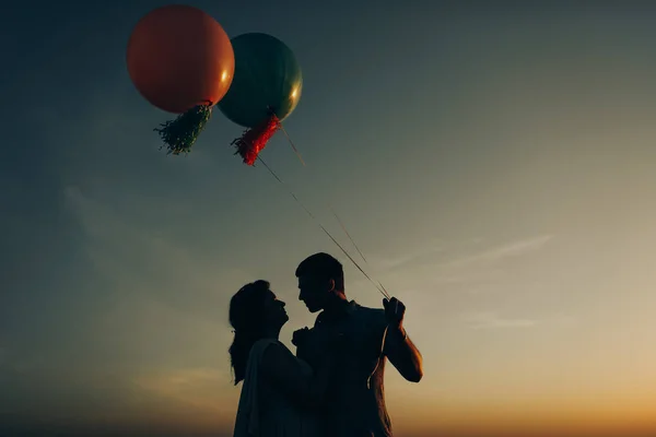 Amante casal de pé no campo com bolas coloridas de hélio — Fotografia de Stock