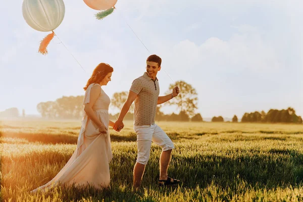 Pareja de amor caminando en el campo con bolas de helio de color — Foto de Stock