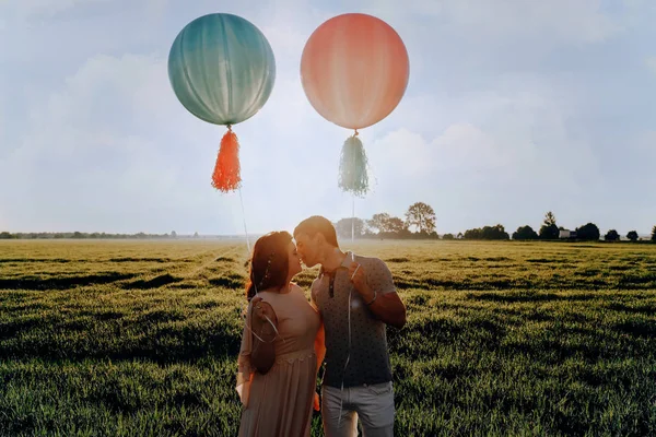 Amante casal de pé no campo com bolas coloridas de hélio — Fotografia de Stock
