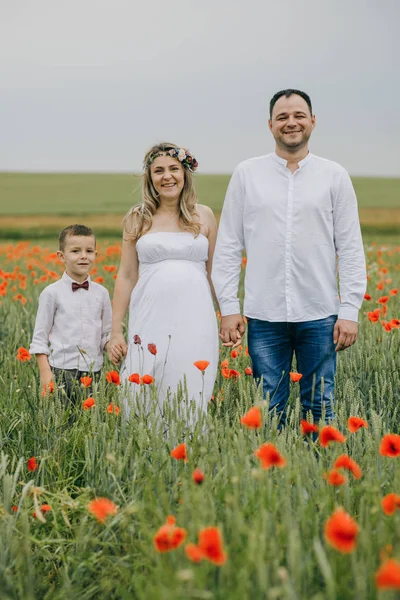 Familia caminando en el campo de amapola tomados de la mano — Foto de Stock