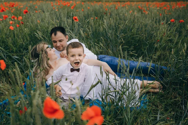 Mladá rodina v červeném makovém poli — Stock fotografie