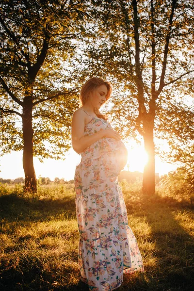 Έγκυος γυναίκα σε ένα πάρκο στο ηλιοβασίλεμα — Φωτογραφία Αρχείου