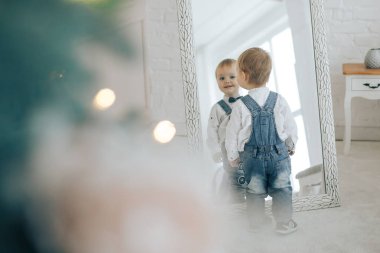 Küçük çocuk kot takım elbiseli ve bir kelebek ve boynunda ile kendini bir ışıltı görüyor