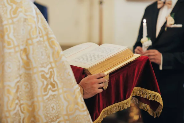 Homem religioso lendo a Bíblia Sagrada e orando na Igreja com velas acesas, religião e conceito de fé — Fotografia de Stock