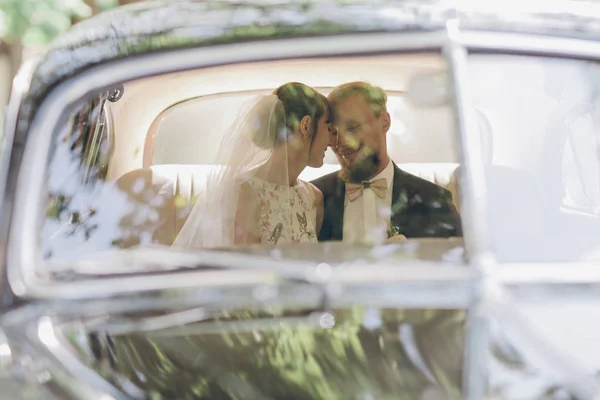 Two young people of burning car in the background. The guy hugs and kisses the girl