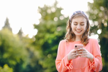 Açık havada akıllı telefon ve yeşil doğa geçmişi kullanan bir kız. Kız Eller akıllı telefon tutuyor. Güzel Yeşil Park 'ta Akıllı Telefon Kullanan Kadın