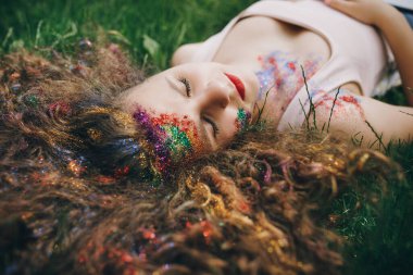 Genç kıvırcık kız çimenlerde yatıyor