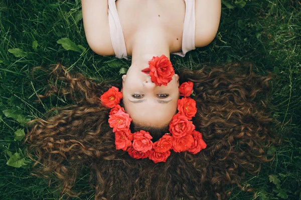 Uma menina bonita nova que jaz na grama com grinalda das flores — Fotografia de Stock