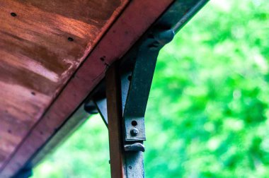 Güneşli bir günde bir ahşap çatı parçası tutan bir demir görünümünü.
