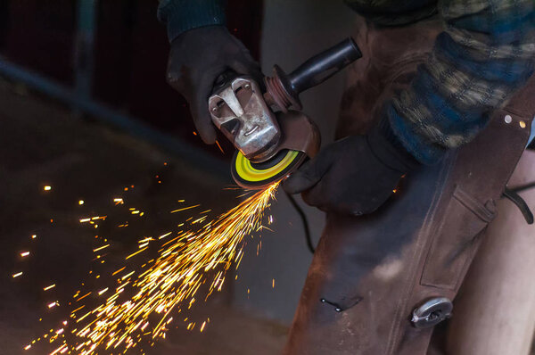 Blacksmith grinding the metal horse shoe peace to shape it.