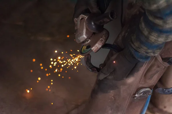 Blacksmith grinding the metal horse shoe peace to shape it.