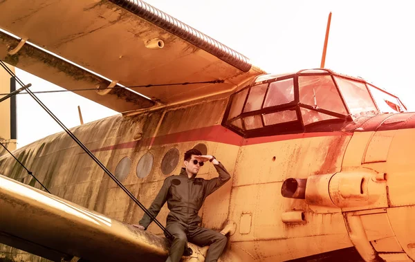 Pohledný mladý pilot sedící na křídlech letadla a skrytý — Stock fotografie
