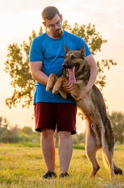 Blick auf einen Mann und einen Schäferhund während eines Sonnenuntergangs — Stockfoto