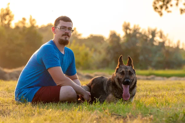 Blick auf einen Mann und einen Schäferhund auf der grünen Wiese — Stockfoto