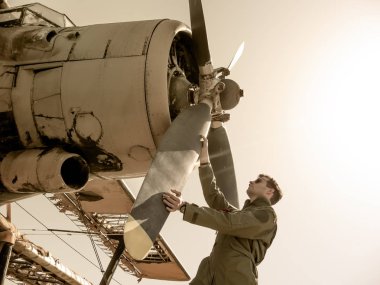 Pervanenin yanında duran yakışıklı genç bir pilot.