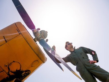 Pervanenin yanında duran yakışıklı genç bir pilot.