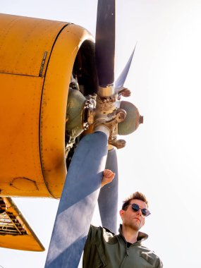 Pervanenin yanında duran yakışıklı genç bir pilot.