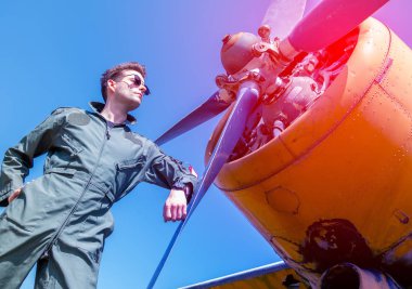 Pervanenin yanında duran yakışıklı genç bir pilot.