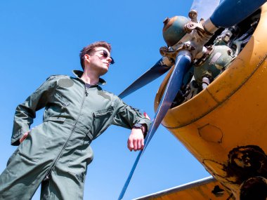 Pervanenin yanında duran yakışıklı genç bir pilot.