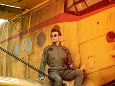 Bir uçağın kanadında oturan yakışıklı bir genç pilot