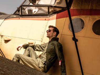 Bir uçağın kanadında oturan yakışıklı bir genç pilot