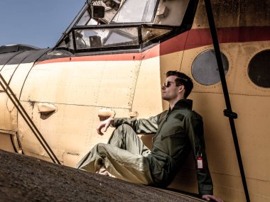 Bir uçağın kanadında oturan yakışıklı bir genç pilot