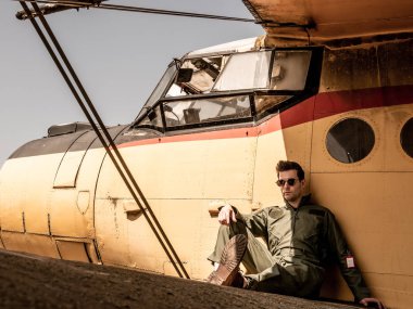 Bir uçağın kanadında oturan yakışıklı bir genç pilot