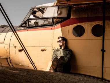 Bir uçağın kanadında oturan yakışıklı bir genç pilot