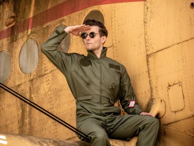 Bir uçağın ve coveri kanadında oturan yakışıklı bir genç pilot