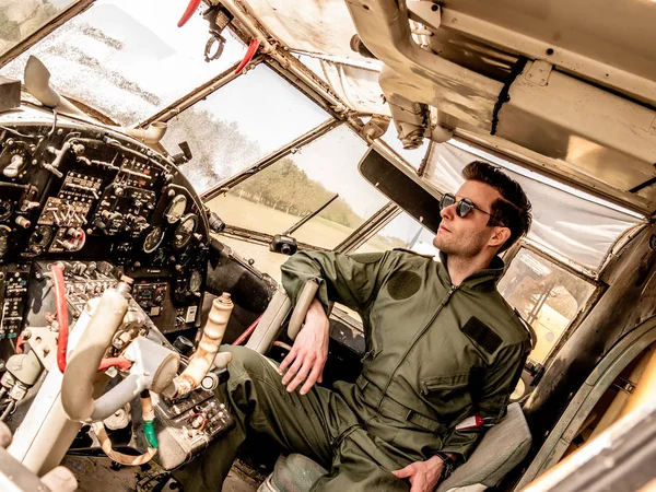 Un piloto joven y guapo sentado en la cabina — Foto de Stock