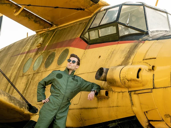 Un joven piloto guapo parado junto a un viejo avión — Foto de Stock