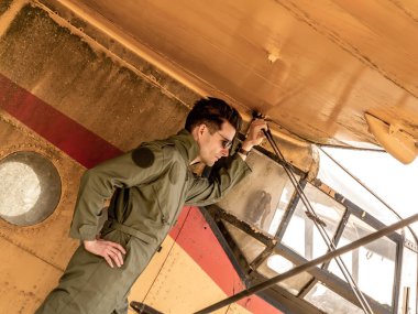 Bir uçağın kanadında duran yakışıklı genç bir pilot